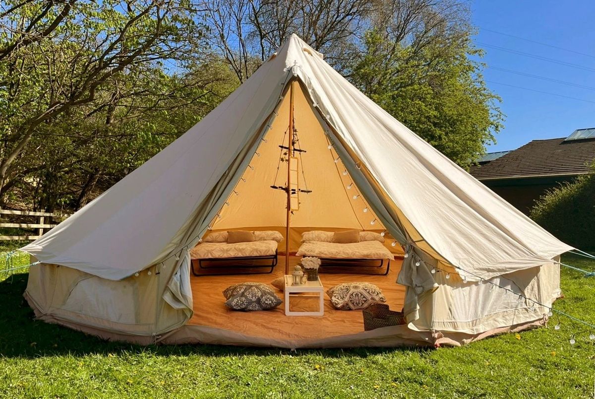 A made-up bell tent: two beds, rugs, cushions and a mirror